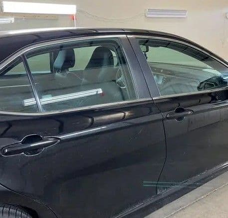 Black sedan parked in a garage, showcasing sleek design and tinted windows.