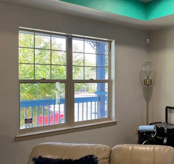 Bright living room with window showing greenery outside and light fixture nearby.