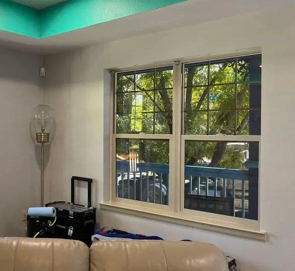 Cozy living room with light beige couch, two large windows, and a modern lamp.