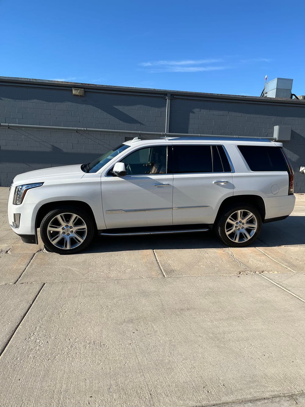 White luxury SUV parked on concrete, showcasing sleek design and chrome wheels.