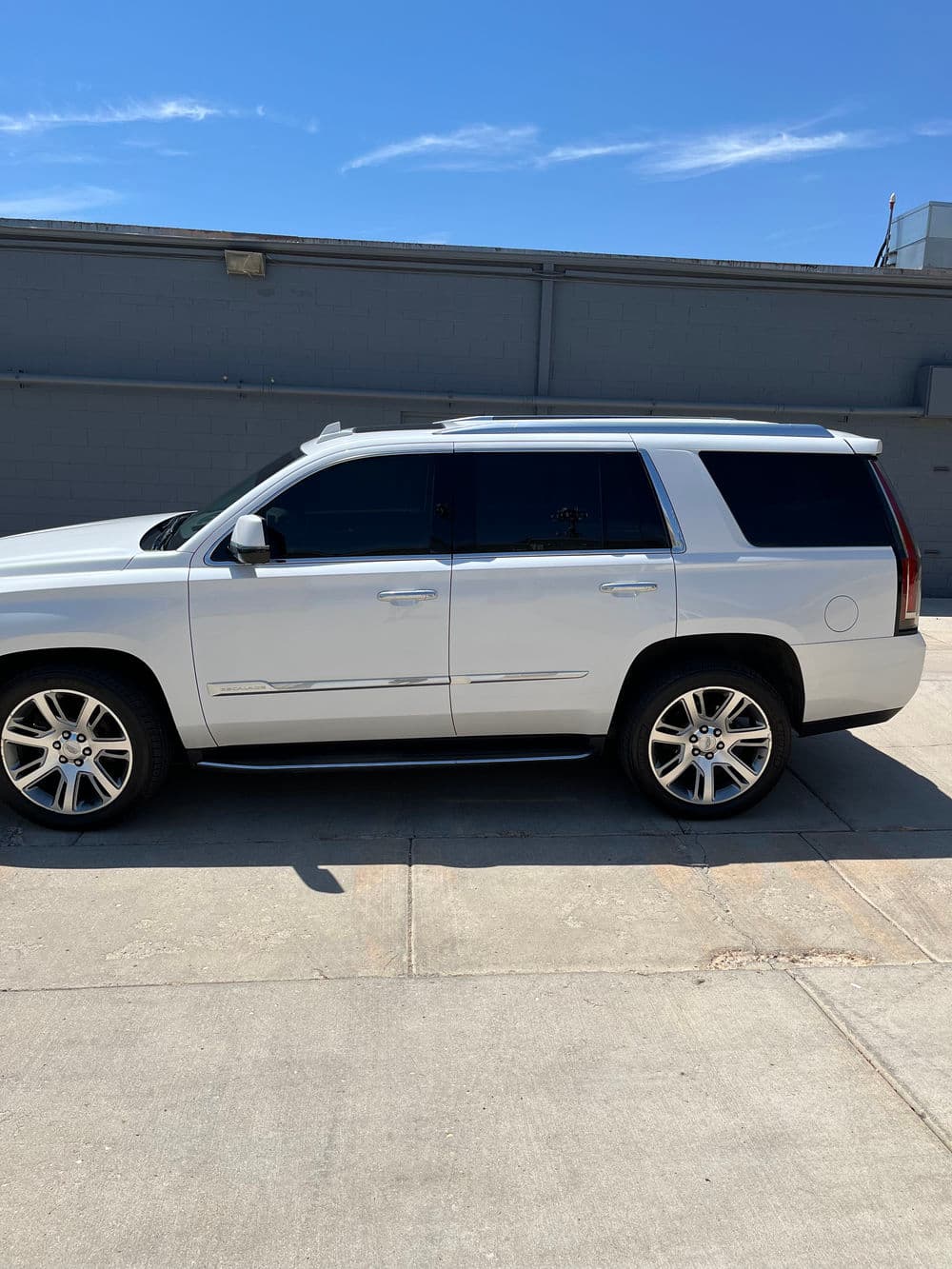 White luxury SUV parked outdoors, showcasing tinted windows and modern design features.